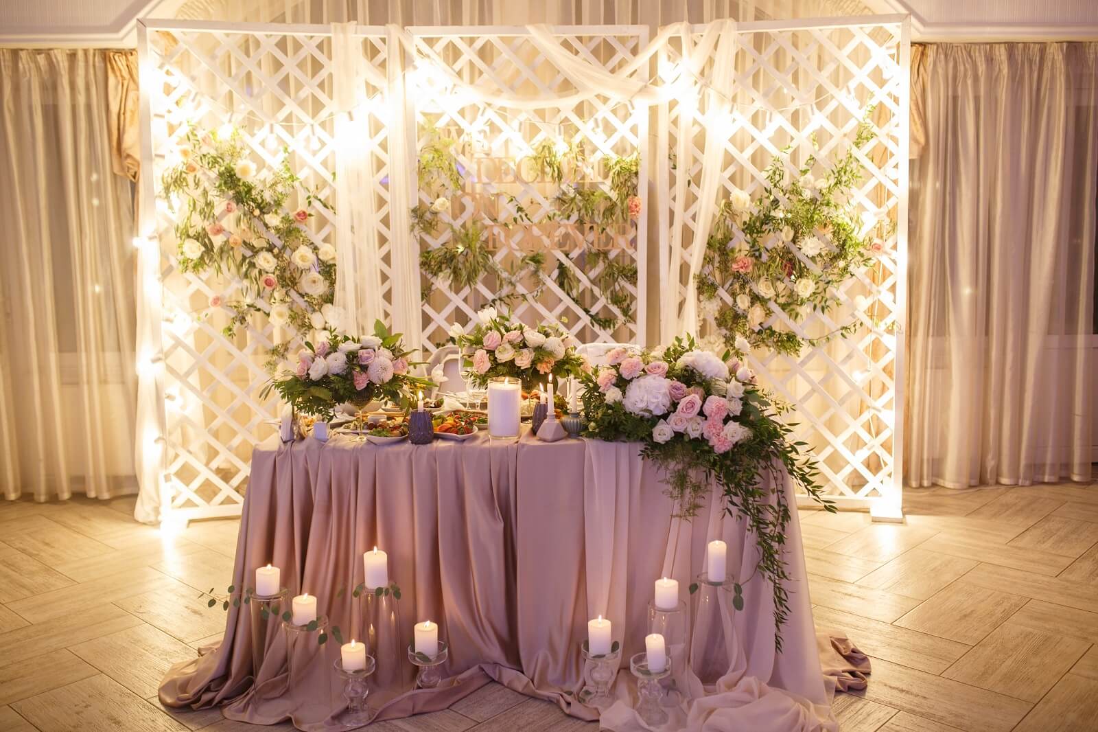 Enticing Wedding Table Décor With Lavender Fabric, Glass Vase, Leaf Garland, Flowers & Candles