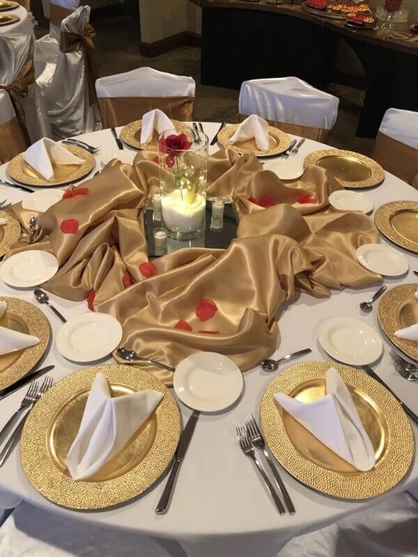 Gold & White Themed Table Setup Using Tablecloth, Fabric, Chargers, Vase, Chair Covers, & Sashes 