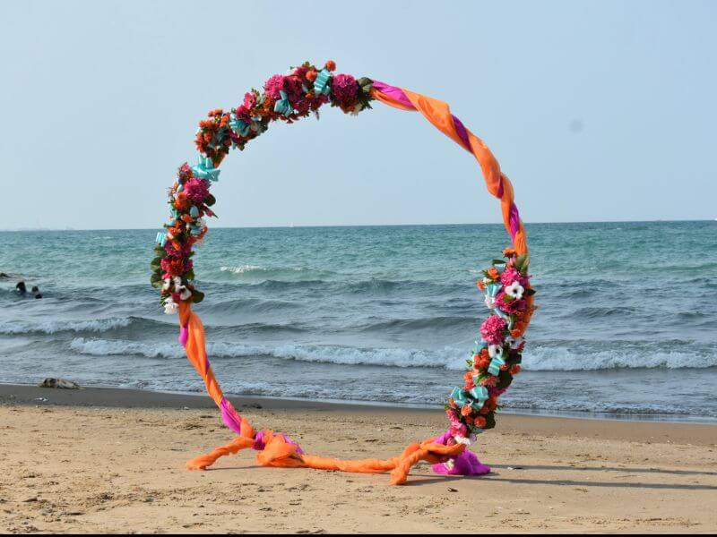 Trendy Beach Arch Décor With Round Metal Arch, Fushia/Orange Fabric, Ribbons & Flower arrangement