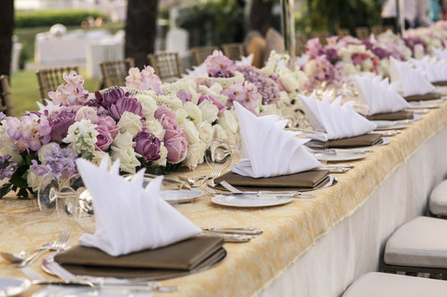 long banquet table with white tablecloth and flower centerpieces