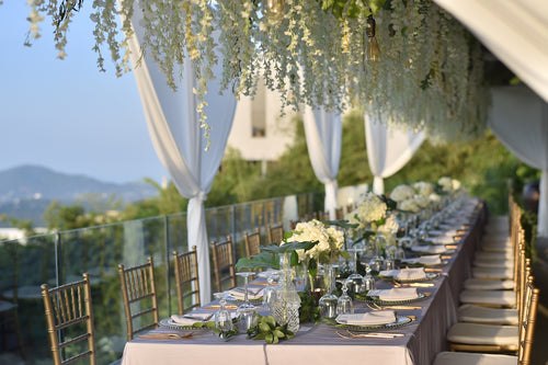 banquet table with tablecloths and glass flower vase centerpiece